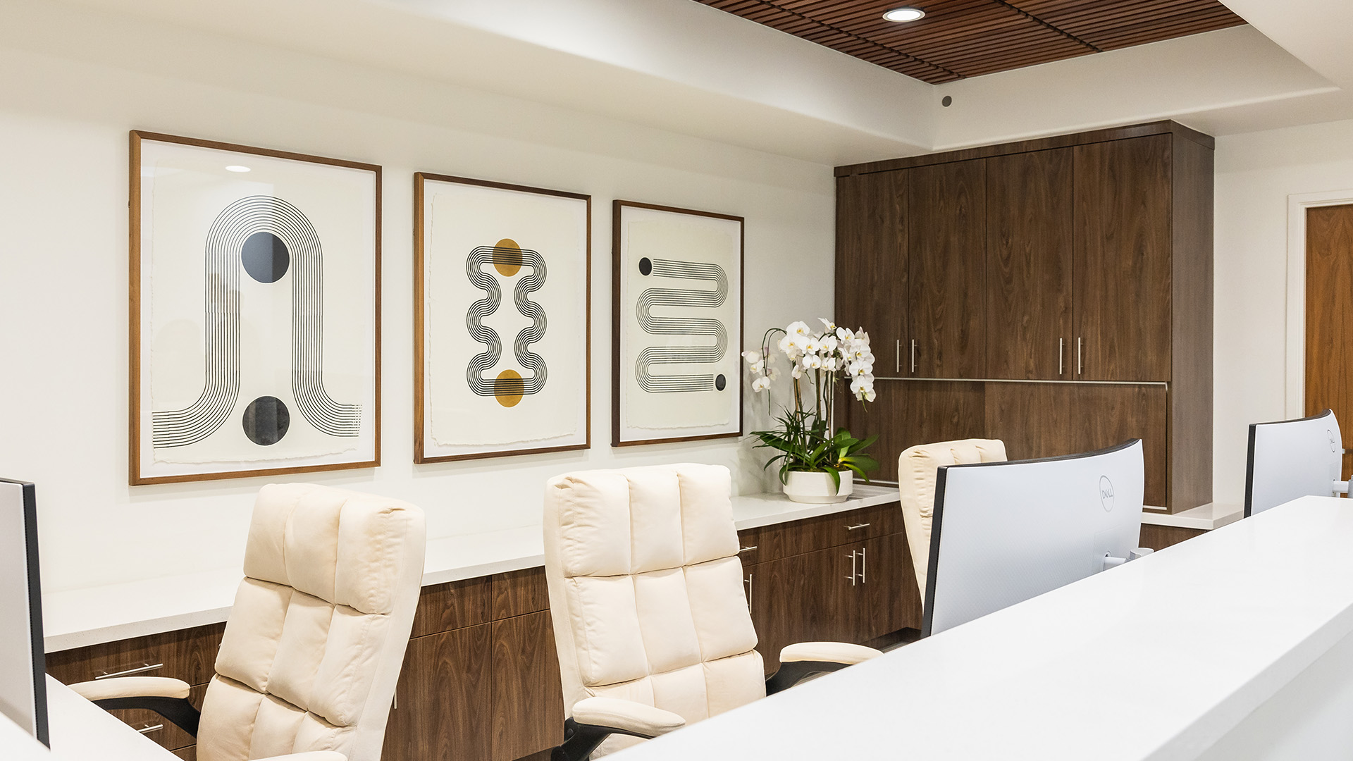 The image shows an interior office space with modern decor, featuring abstract art on the wall, contemporary furniture, and a professional setting.