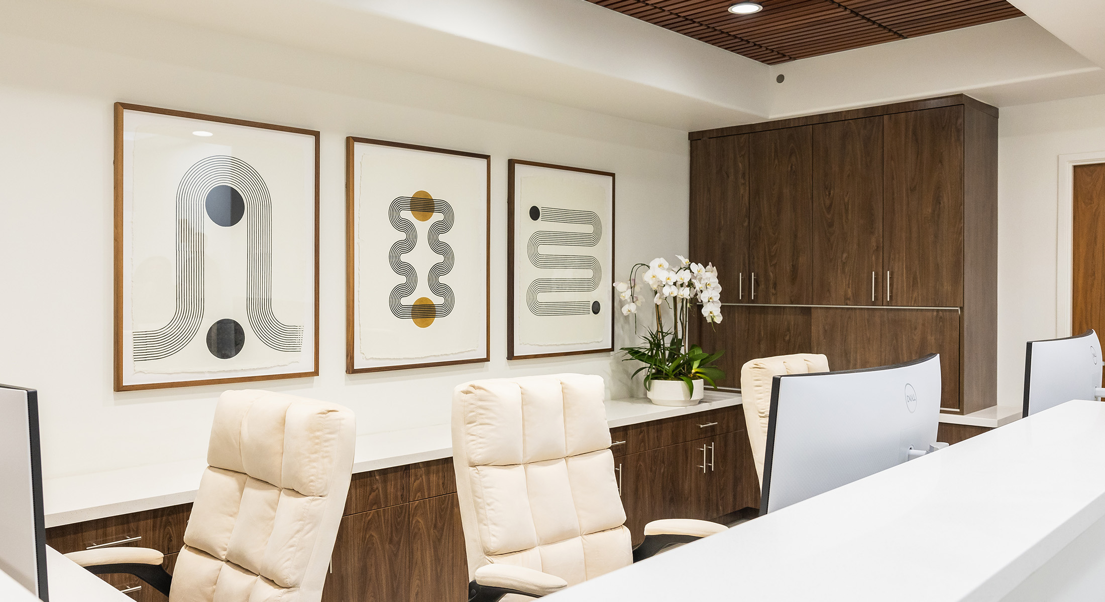 The image displays an interior office space with modern furnishings, including a desk, chair, and framed artwork on the walls.